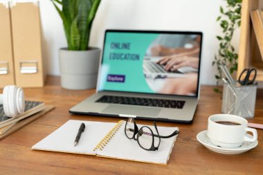 Boş sayfalarda kalem ve gözlüklü dizüstü bilgisayarı ve dizüstü bilgisayarın arka planında bir fincan kahve yi açın