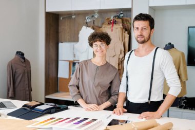 Birlikte çalışırken kamera önünde masa başında duran giyim öğeleri iki genç yaratıcı tasarımcılar