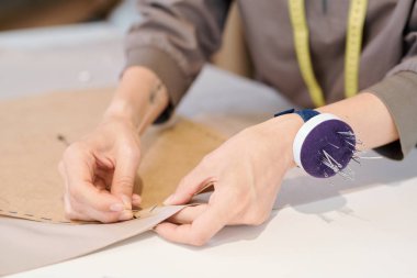 Atölyede yeni giysi modeli üzerinde çalışırken tekstile kesilmiş kroki genç terzi nin elleri