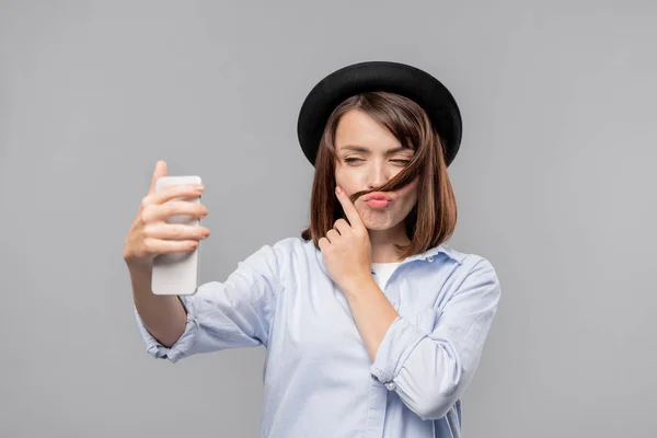 Jovem Morena Camisa Chapéu Divertindo Com Cabelo Enquanto Faz Selfie — Fotografia de Stock