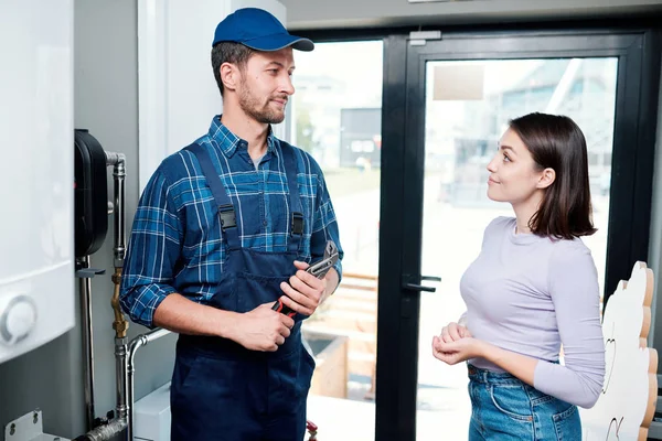 Genç rahat ev hanımı mutfak ekipmanları ile ona sorun açıklamadan önce teknisyen veya tesisatçı bakarak