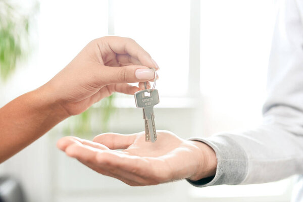 Close-up of unrecognizable real estate agent passing flat key to tenant, rent apartment concept