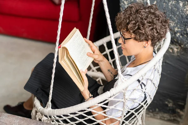 Pretty Young Brunette Woman Casualwear Sitting Hanging Armchair While Reading — Stock Photo, Image