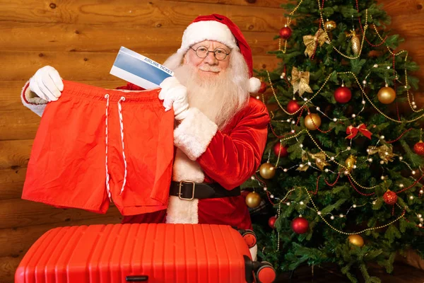 Счастливый Санта Показывает Один Рождественских Подарков Красные Шорты Билеты Самолет — стоковое фото