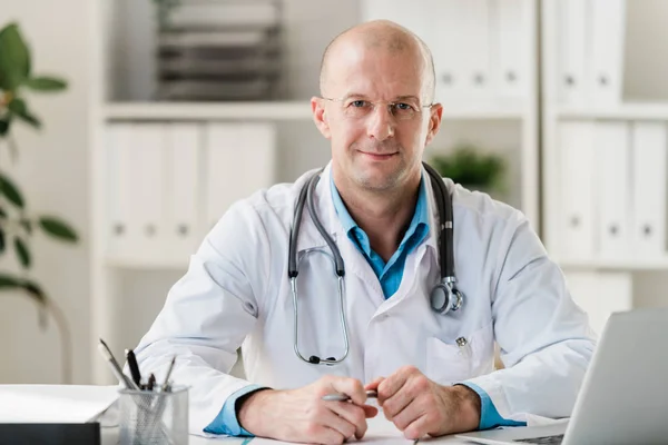Skallig Professionell Läkare Med Penna Sittande Vid Skrivbord Läkarmottagning Eller — Stockfoto