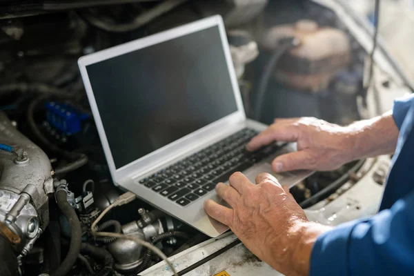 技術情報を検索する際にラップトップのキーボード上の車の修理サービスの成熟したマスターの手 — ストック写真