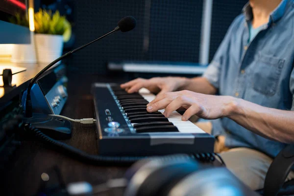 年轻的男性音乐家一边坐着一边触摸钢琴键盘的键 一边记录新的音乐 — 图库照片