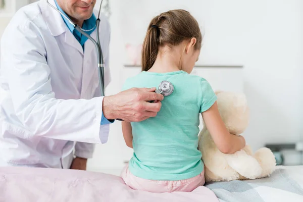 Mladý Pediatr Bílém Plášti Vyšetřuje Záda Malé Holčičky Stetoskopem Lékařské — Stock fotografie