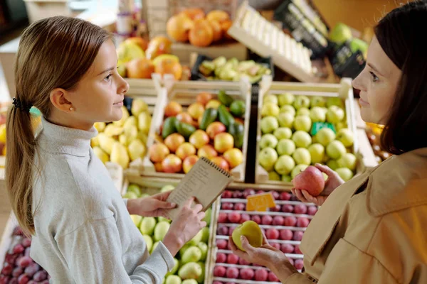 Fiatal Barna Almával Nézi Lányát Bevásárlólistával Miközben Gyümölcsöt Választ Szupermarketben — Stock Fotó