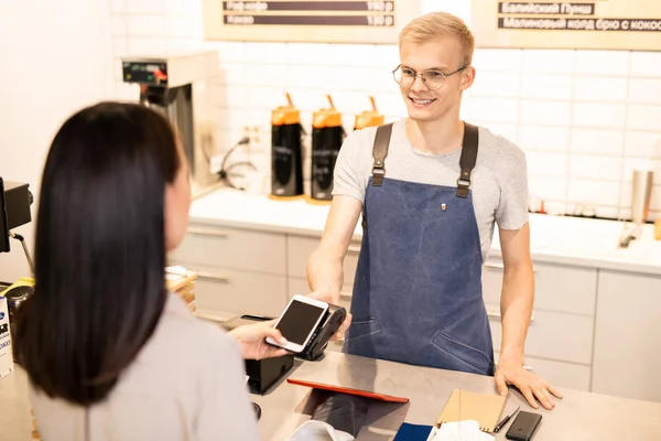 Happy Young Barista Looking Client Paying Drink While Holding Smartphone — Stock Photo, Image