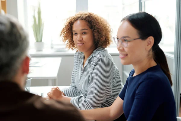 Two Young Multicultural Businesswomen Sitting Desk While One Them Looking — Stock Photo, Image