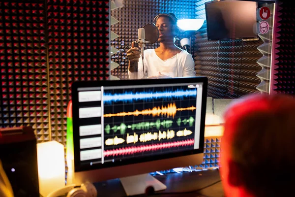 Joven Hombre Afroamericano Con Auriculares Cantando Micrófono Mientras Productor Graba — Foto de Stock