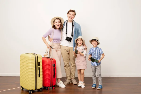 若いです興奮した家族の2人の両親と彼らのかわいい子供ですカジュアルウェアでスーツケース旅行の準備 — ストック写真