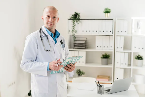 Joven Practicante Serio Terapeuta Uniforme Tomando Notas Documento Mientras Trabaja — Foto de Stock