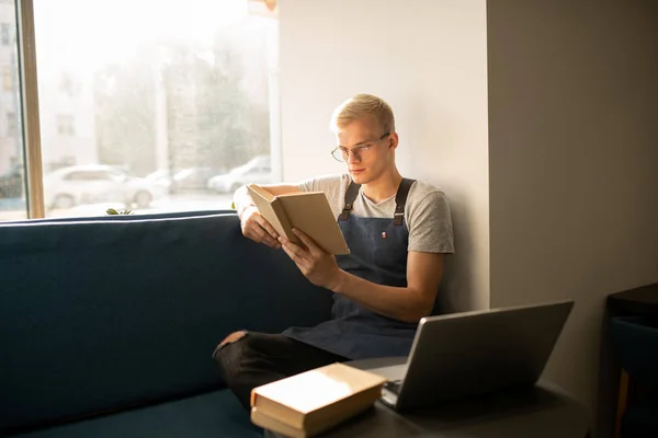 Joven Trabajador Serio Cafetería Sentado Junto Ventana Mientras Lee Libros — Foto de Stock