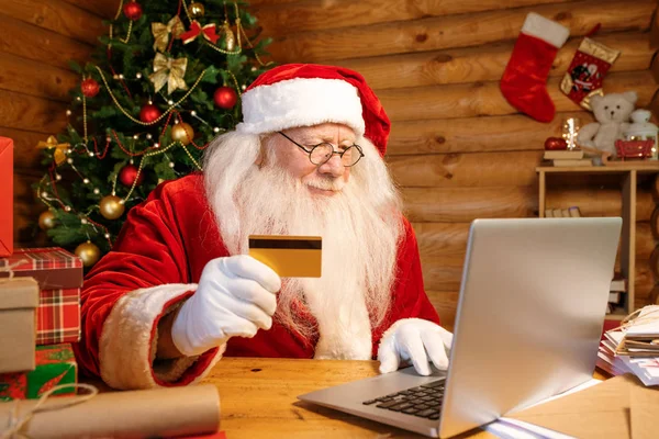 圣诞前夕 圣诞老人身穿盛装 手持塑料卡片在网上下订单 — 图库照片