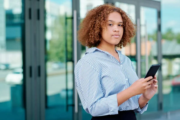 Jovem Mulher Negócios Intercultural Séria Com Smartphone Olhando Para Você — Fotografia de Stock