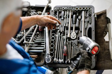 Yetişkin profesyonel teknisyenlerin elleri, onarımları gerçekleştirmeden önce bazı detaylardan başlık seçiyorlar.