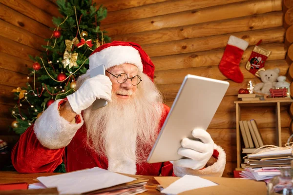 Мобильный Санта Клаус Гаджетами Сидит Столом Просматривает Онлайн Подарки Делает — стоковое фото