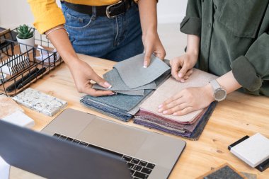 İç tekstil örneklerini inceleyen iki genç ve yaratıcı kadının elleri. Yeni müşteri evi mobilyaları için birini seçerken.