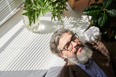 Mutlu, olgun, rahat iş adamı ya da gri saçlı ve sakallı başka bir profesyonel ofiste çalıştıktan sonra kafasını pencere eşiğine koyuyor.