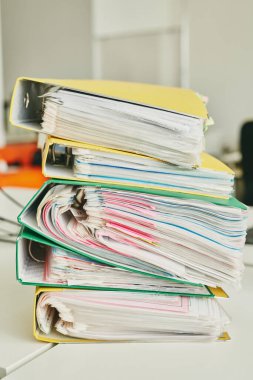 Ofisine yapıştırıcı notlar iliştirilmiş dosyalarla dolu renkli klasörler içeren tabloyu kapat