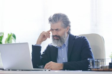 Baş ağrısı çekerken ya da bir şey hatırlamaya çalışırken gri sakallı, saçı olan yorgun ya da düşünceli yaşlı bir adam tapınağa dokunuyor.