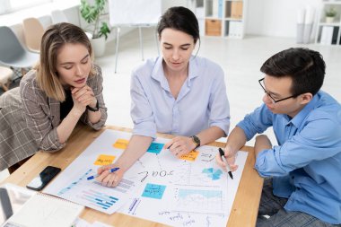 İki genç kadın ve işadamı iş amaçlarına sahip büyük bir gazeteye bakarken aynı zamanda beyin fırtınası yapıyor ve buluşmada yeni fikirleri tartışıyorlar.