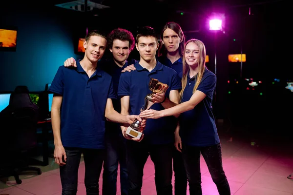 五位年轻 成功的电子竞技比赛得奖者站在俱乐部摄像机前举着金像奖雕像 — 图库照片