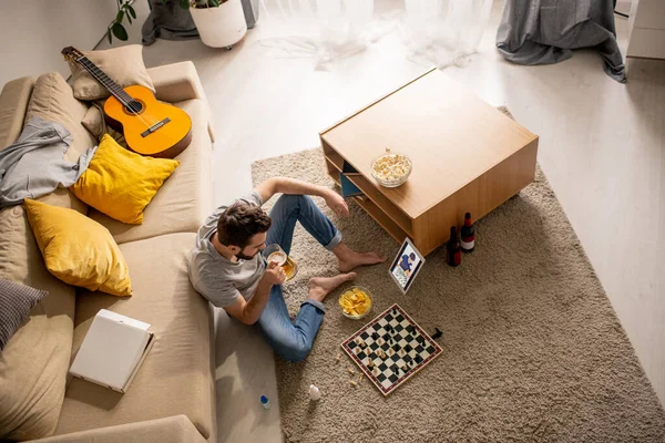 Vista Superior Del Joven Sentado Sala Estar Bebiendo Cerveza Mientras — Foto de Stock