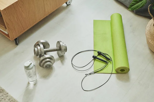 两个金属哑铃 塑料水瓶和滚动式绿色垫子 供在客厅地板上锻炼用 — 图库照片