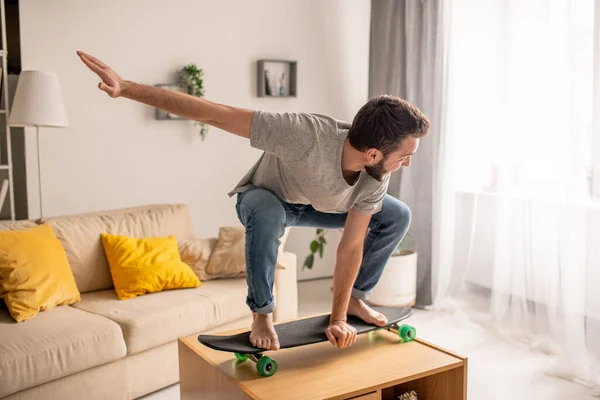 Despreocupado Joven Barbudo Skate Hombre Pose Agachada Mesa Café Sala — Foto de Stock