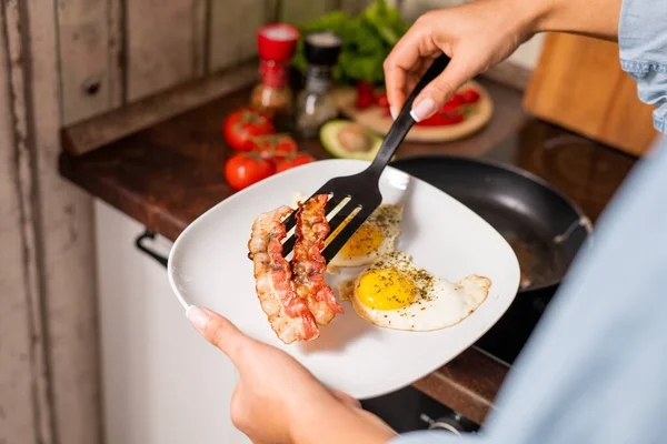 Händer Unga Hona Sätta Stekt Bacon Och Ägg Tallrik När — Stockfoto