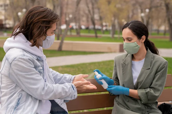 Mujer Joven Con Guantes Protectores Mascarilla Rociando Desinfectante Las Manos —  Fotos de Stock