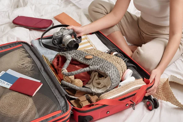 夏休みの準備をしながら 認識できない女性がベッドの上で足を組んで座ってスーツケースのものをチェックする — ストック写真