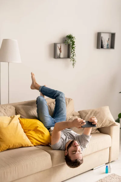 Joven Serio Con Ropa Casual Sentado Boca Abajo Sofá Jugando — Foto de Stock