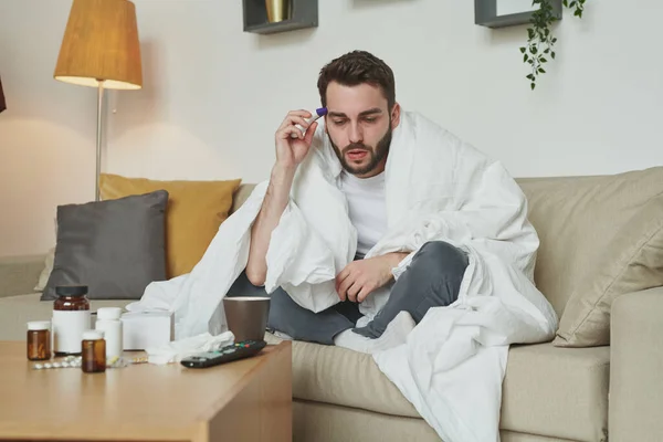 Homem Doente Embrulhado Cobertor Quente Temperatura Medição Enquanto Sentado Sofá — Fotografia de Stock