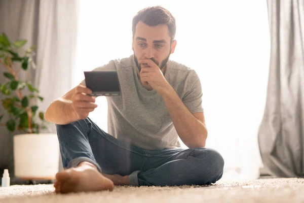 Allvarlig Pensiv Ung Man Sitter Mattan Och Lutar Huvudet Hand — Stockfoto