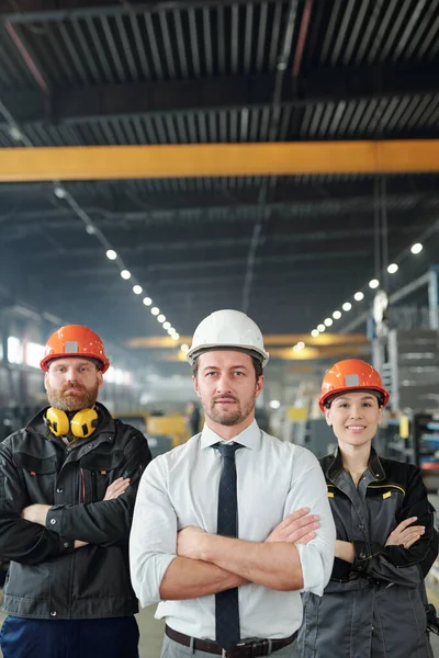在当代大型工厂的车间里 由戴着硬礼帽 手挽手的专业人员组成的自信的工厂团队 — 图库照片