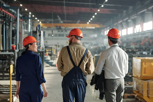 Zadní Pohled Průmyslové Inženýry Hardhats Procházky Továrně Shop Při Diskusi — Stock fotografie