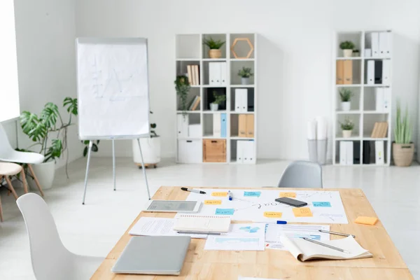 ホワイトボードとのビジネスミーティングのための大規模な現代的なオフィスの一部 ガジェットとテーブルの周りの椅子 ペンと紙 — ストック写真
