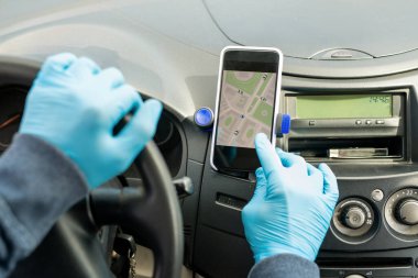 Çağdaş taksi şoförünün eldivenli elleri akıllı telefonun ekranına dokunurken navigatör uygulamasını kullanarak istemcinin adresini buluyor