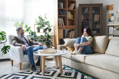 Gündelik kıyafetli genç bir bayan danışmanın ofisinde oturuyor ve onunla sorunlarını konuşuyor.