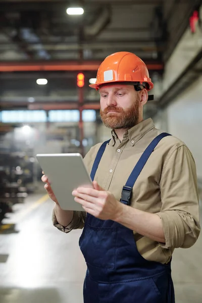 Beschäftigter Junger Fabrikarbeiter Overalls Checkt Arbeitsdatei Auf Tablet Während Der — Stockfoto