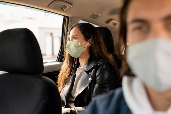 Wanita Muda Dengan Earphone Dan Topeng Pelindung Melihat Melalui Jendela — Stok Foto