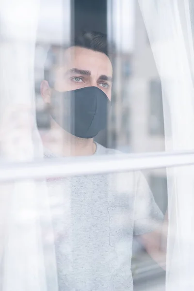 Een Verwarde Jongeman Met Een Beschermend Masker Voor Het Raam — Stockfoto