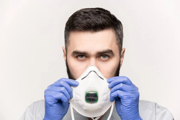 Serious Young Man Medical Uniform Protective Gloves Putting Respirator Face — Stock Photo, Image