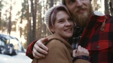 Sevgili çiftin sonbaharda güzel bir ormanda eğlenirken, birbirlerine sarılırken, konuşurken ve gülümserken, el kamerasıyla çekilen orta ölçekli fotoğrafı.