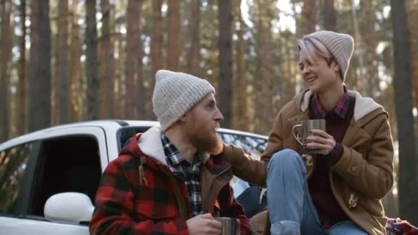 中のショットの若いカップルでビーニーでリラックスした森林道 お茶やホットチョコレートを飲み — ストック動画