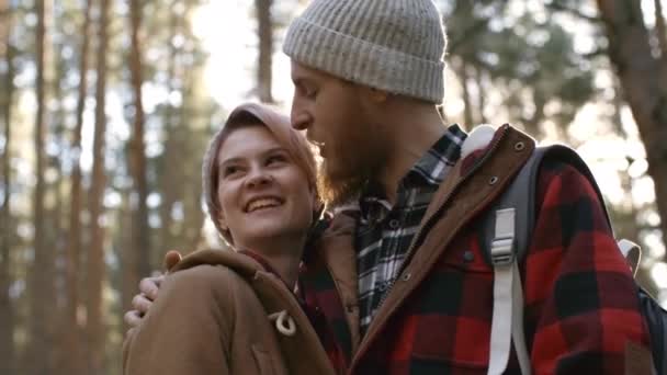 森の道の車の近くに立つ若い白人夫婦の中での撮影 抱っこや森の景色を楽しみながら話す — ストック動画